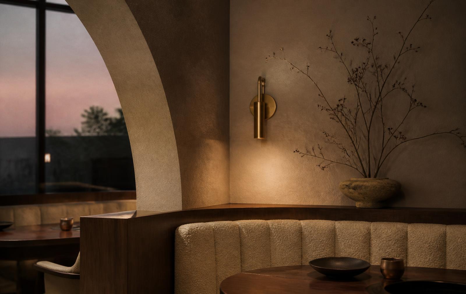 Restaurant alcove with curved archway and brass lamp at dusk